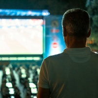 sitting-man-watching-football-public-place-night 1